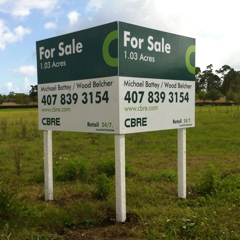 Two-sided for-sale land sign on white posts in an open lot